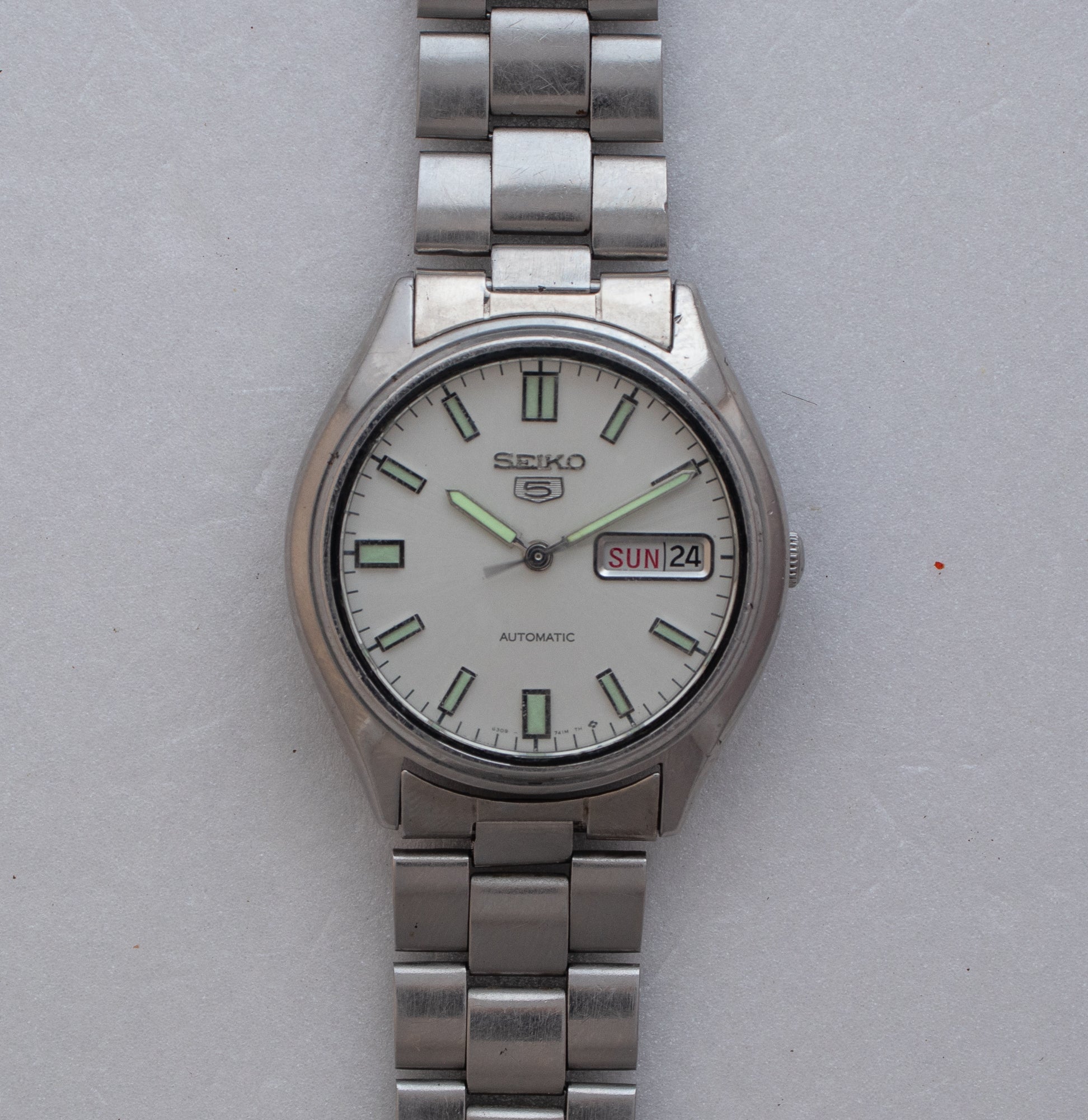 Silver Seiko watch on a light gray background