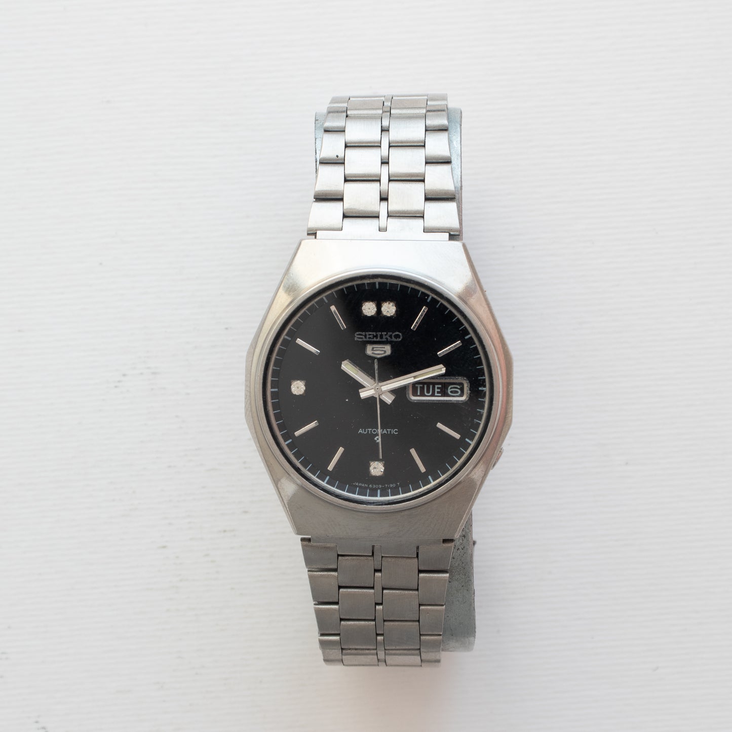 Silver Seiko watch with a black face on a white background