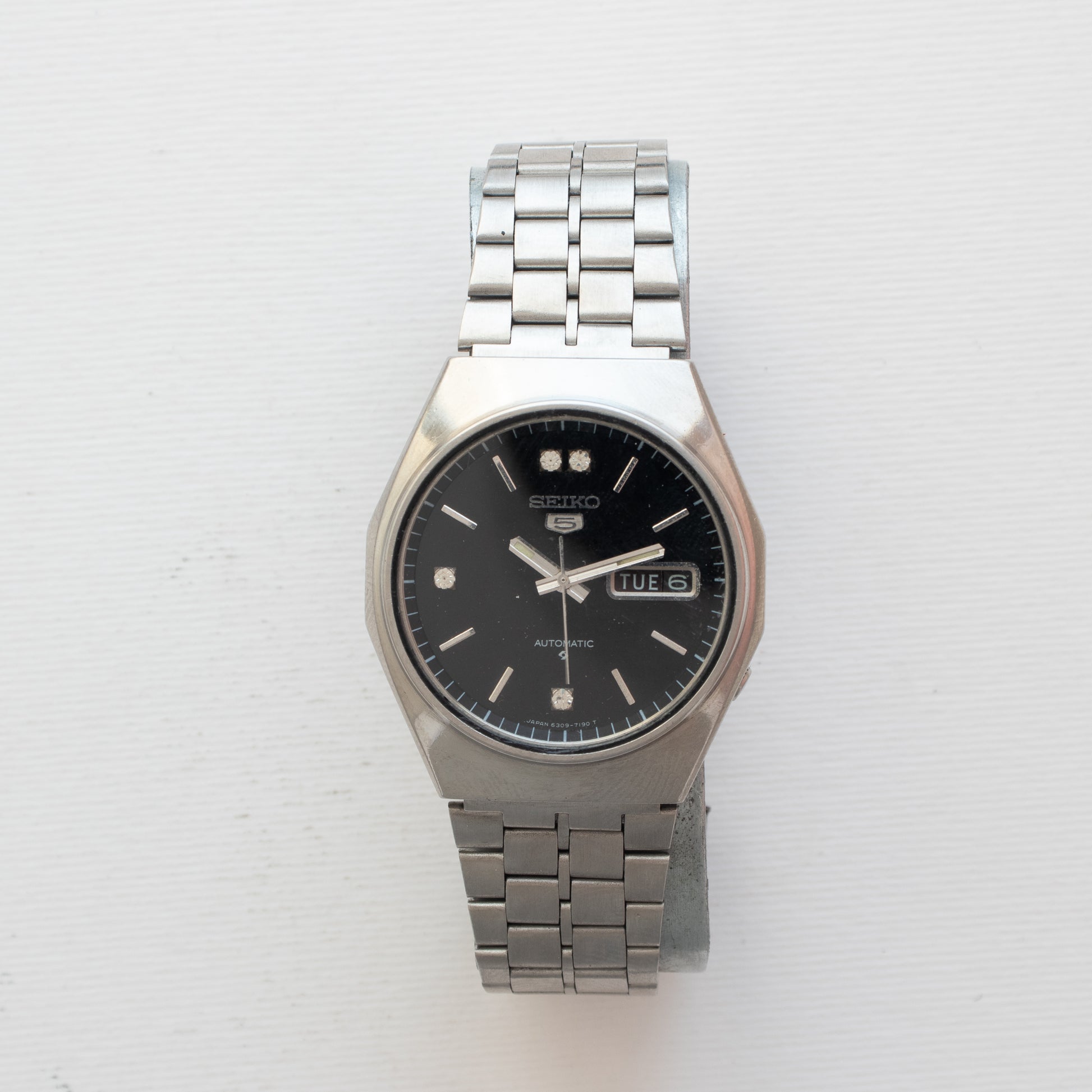 Silver Seiko watch with a black face on a white background
